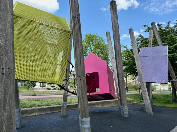 Modular floating yellow, pink, and purple play houses with rope bridges connecting them