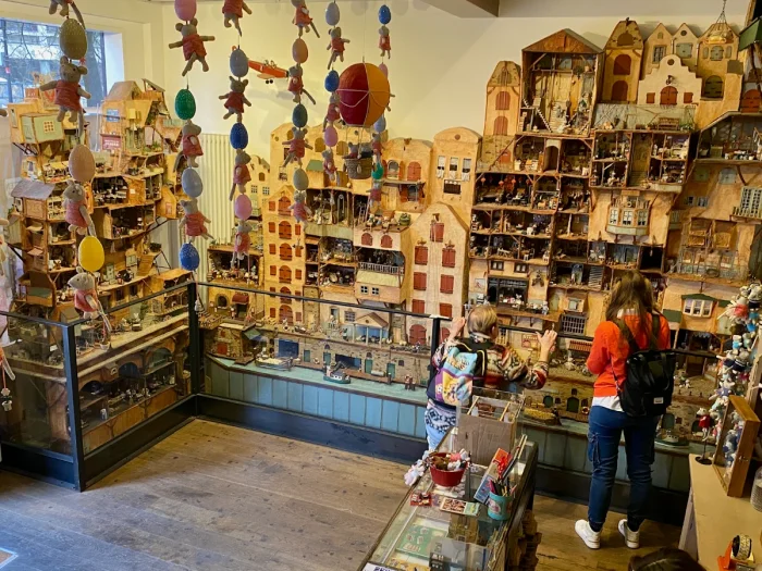 Mom and daughter browsing museum showcasing whimsical mouse village with canal houses behind glass barrier