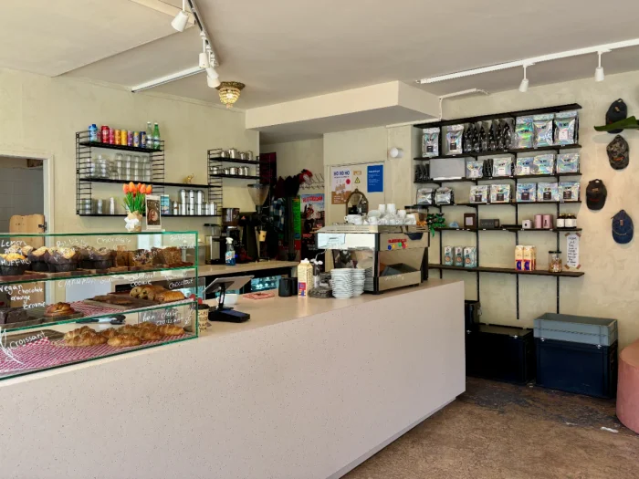 Modern and bright coffee shop interior with pastries on display and shelves of merchandise