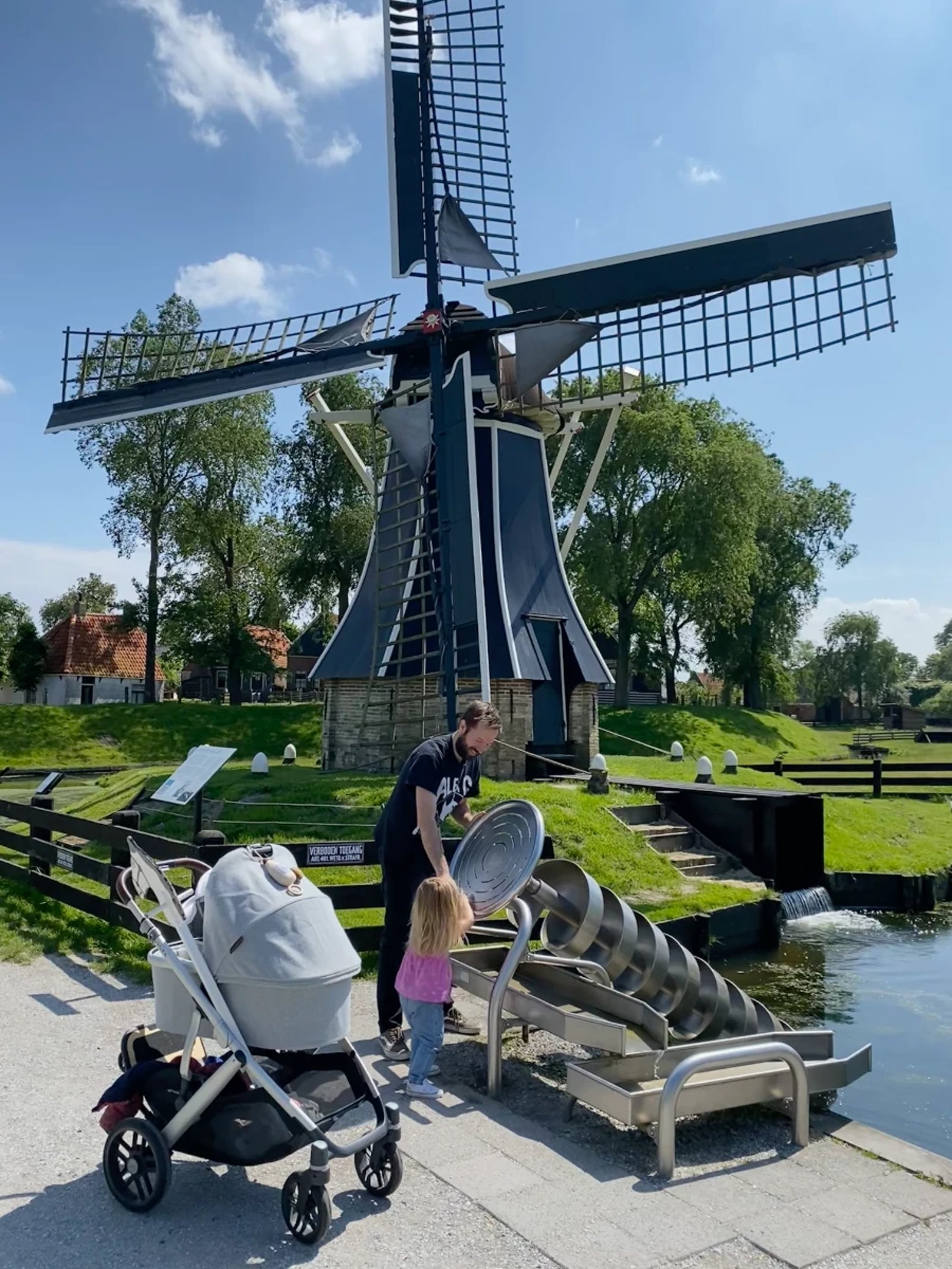 Family spins a giant screw-shaped water wheel with blank windmill behind