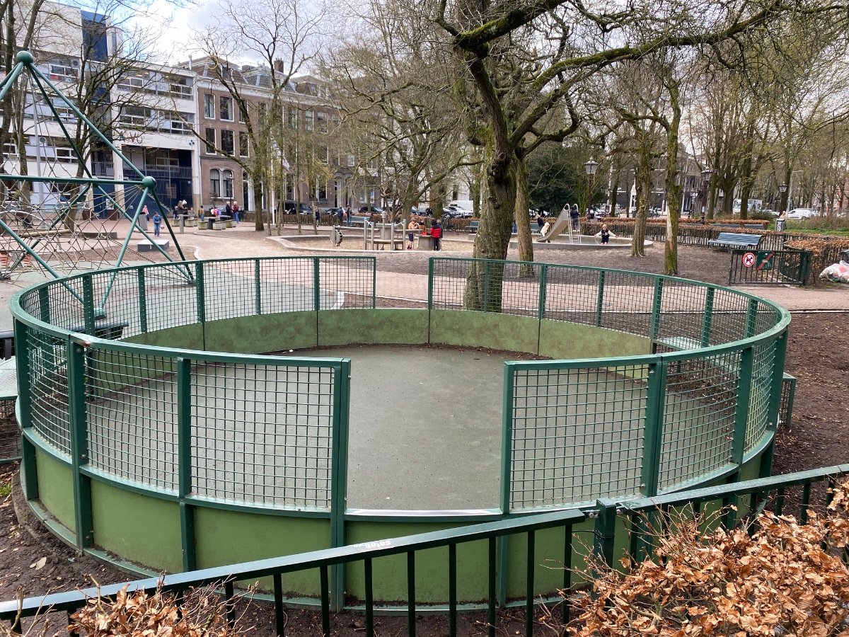 Round, green mini-football pitch with metal enclosure