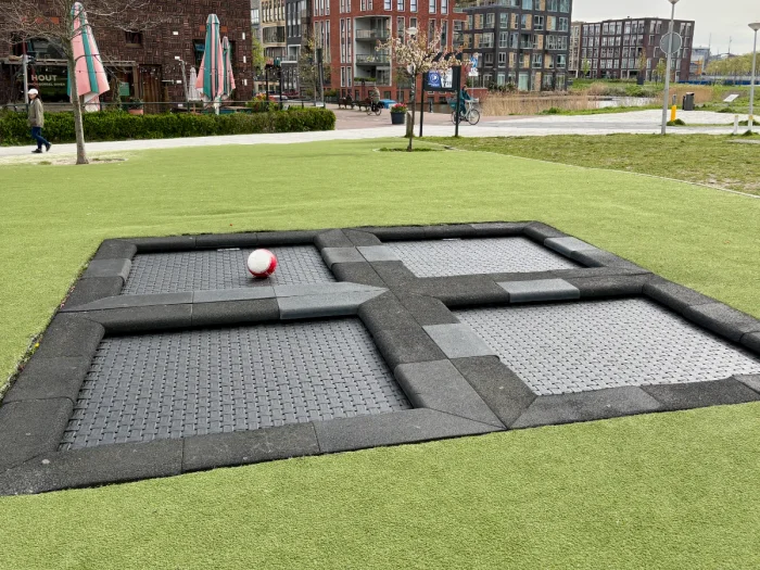 Four small outdoor trampolines set into the ground with astroturf arround