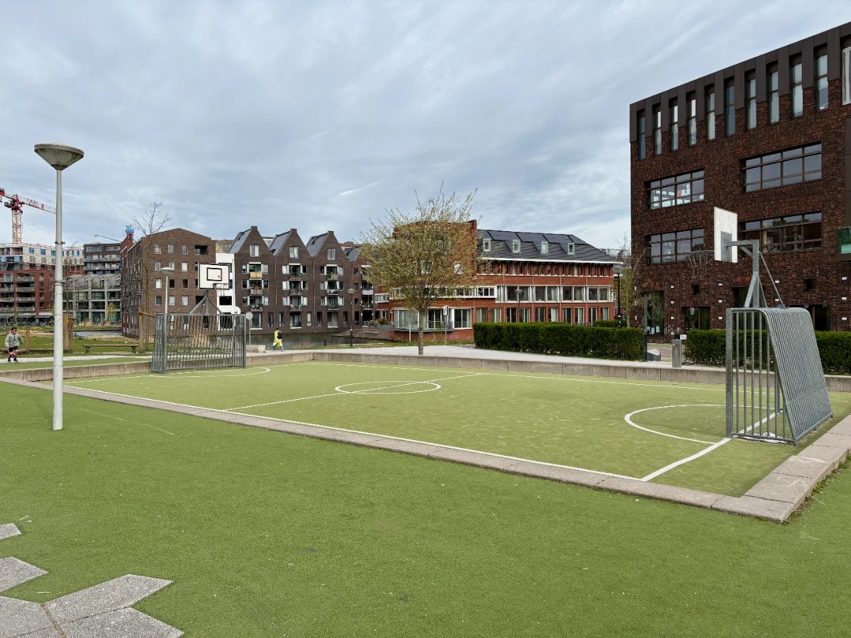 Children's football pitch in park with houses in the distance and lamp post beside