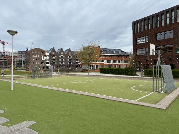 Children's football pitch in park with houses in the distance and lamp post beside