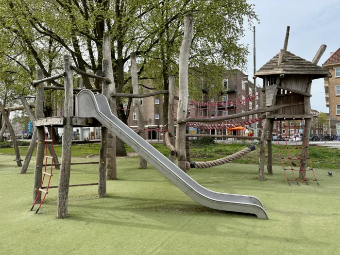 Wooden play structure with metal slide, treehouse, rope bridges