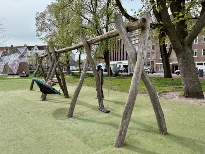 Dad swinging kid on rustic wooden swing set with nest swings and regular swing